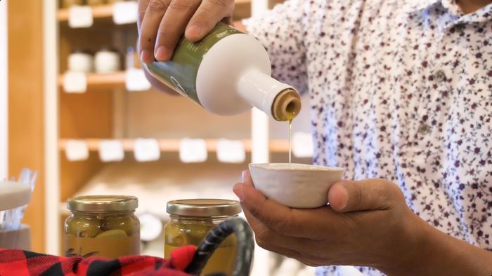 A person is pouring olive oil into a small bowl.
