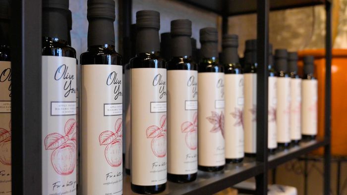 A row of bottles of oil are lined up on a shelf.