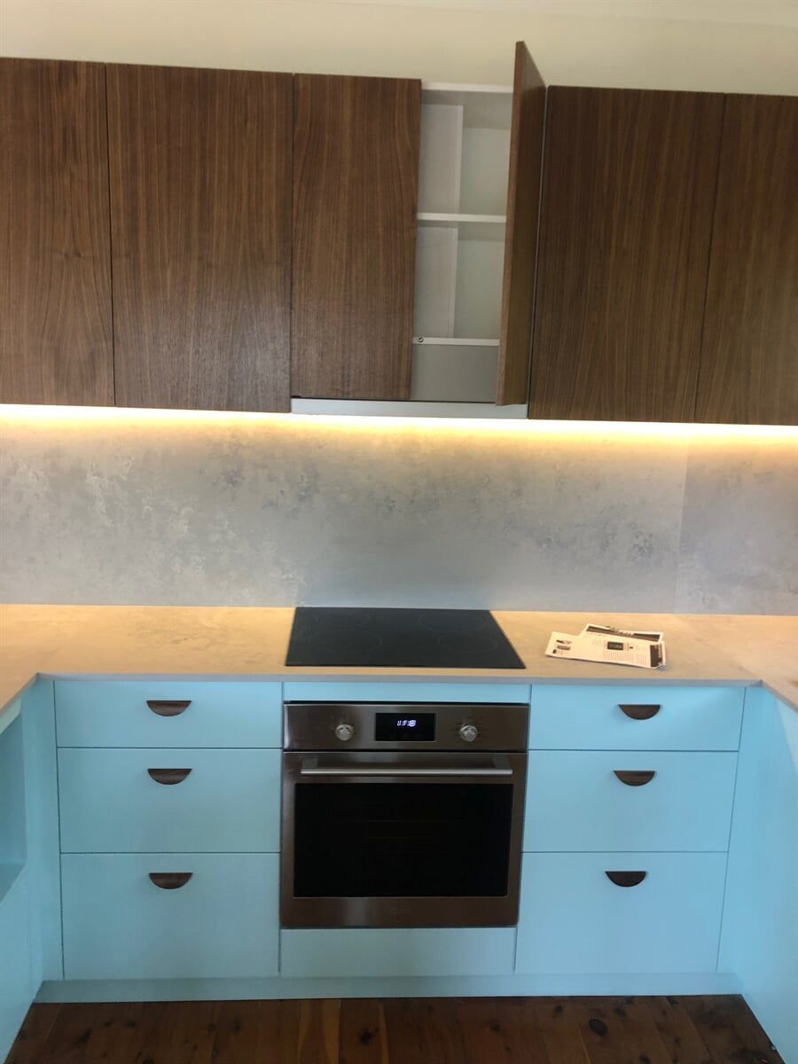 A Kitchen With Blue Cabinets And A Stove Top Oven — L.A.F Electrical P/L In Empire Bay, NSW