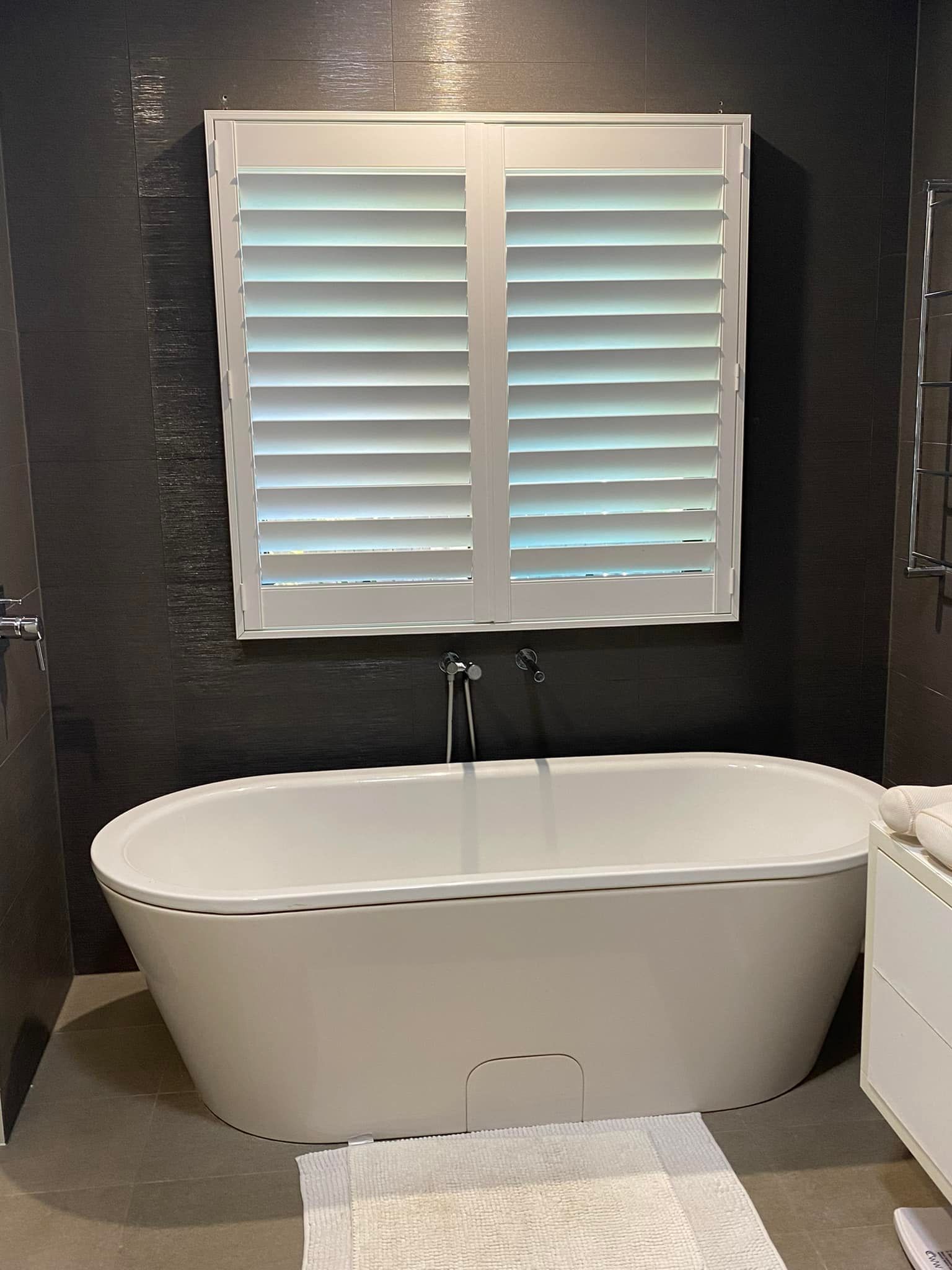 A Bathroom With a Bathtub and a Window With Shutters — Whitsunday Blinds & Security In Beaconsfield, QLD