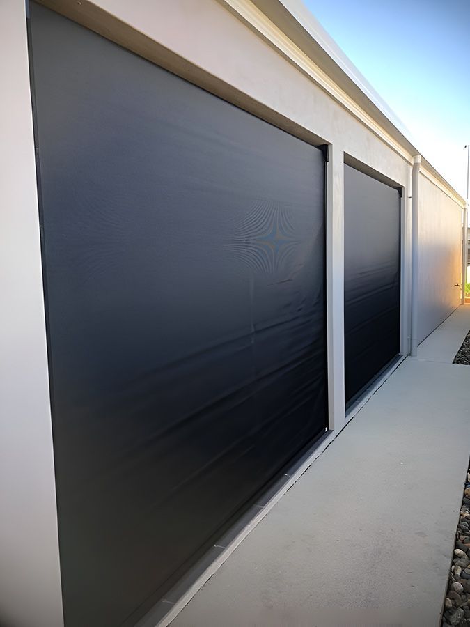A Row of Black Garage Doors on the Side of a Building — Whitsunday Blinds & Security In Beaconsfield, QLD