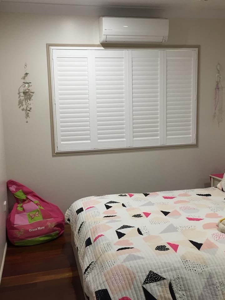 A Bedroom With a Bed, Window, and Air Conditioner — Whitsunday Blinds & Security in Proserpine, QLD