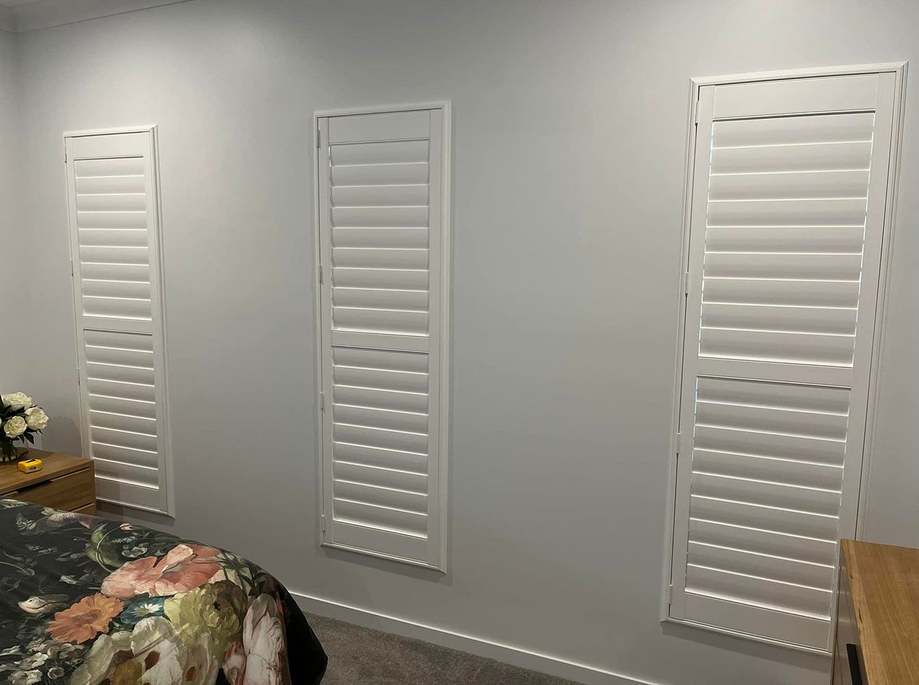 A Bedroom With Three White Shutters on the Windows and a Bed — Whitsunday Blinds & Security in Bowen, QLD