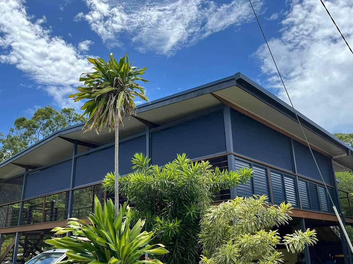 A Large Blue House With a Palm Tree in Front of It — Whitsunday Blinds & Security In Beaconsfield, QLD