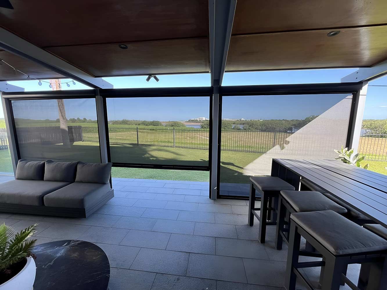 A Patio With a Couch, Stools and a Table With a View of a Field — Whitsunday Blinds & Security In Beaconsfield, QLD
