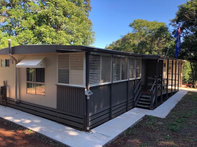 A Small House With Stairs Surrounded by Trees With Window Shutters — Whitsunday Blinds & Security In Beaconsfield, QLD