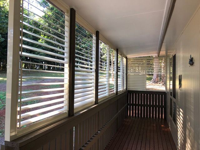 Porch With Shutters on The Windows And a Wooden Deck — Whitsunday Blinds & Security In Beaconsfield, QLD