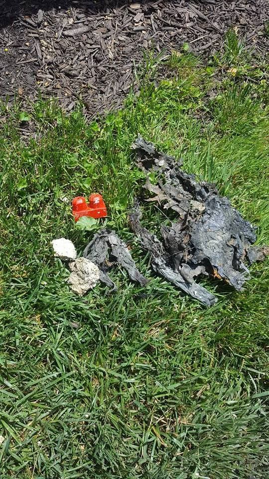 Charred debris and Lego brick on grass.