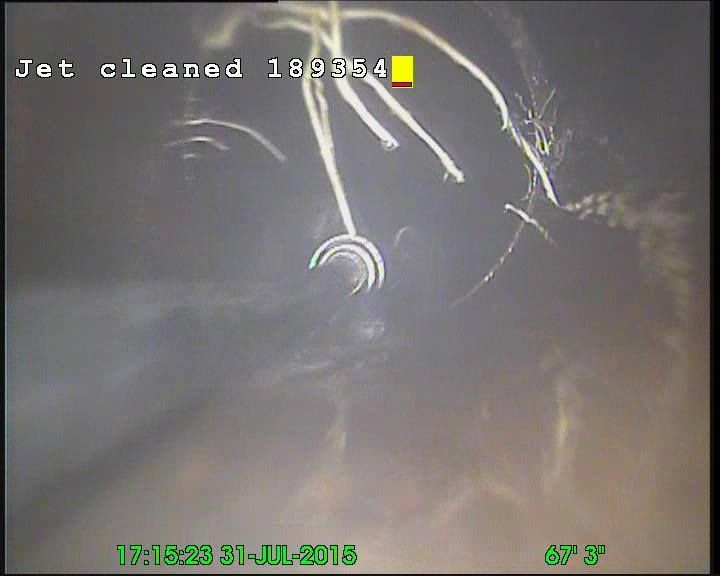 Inside of a pipe, a jet cleans debris. Text reads 