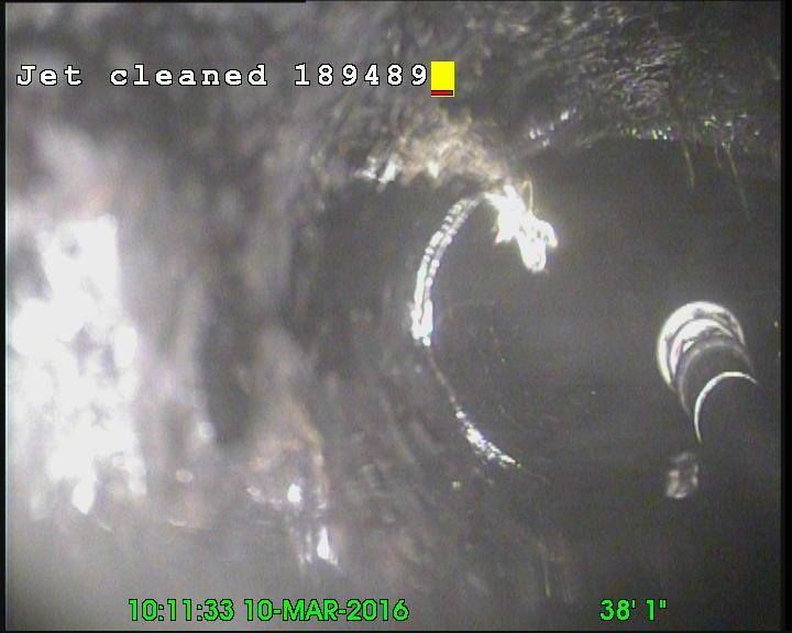 Inside of a pipe being cleaned by a jet. The jet is cleaning out debris.