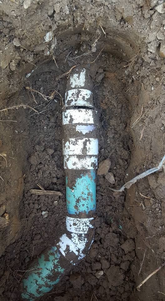 PVC pipe fitting buried in dirt, connecting pipes.