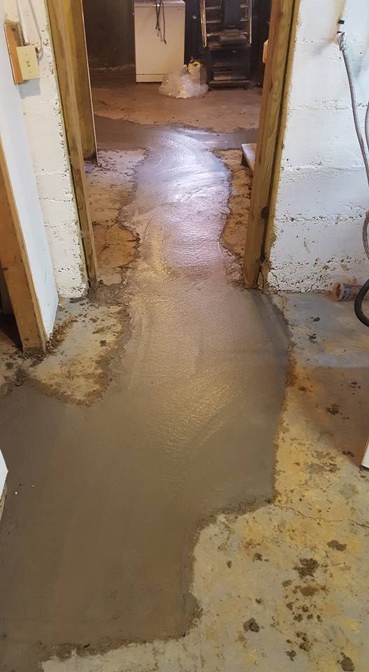 Freshly poured concrete pathway in a basement doorway; light gray concrete, unfinished walls.