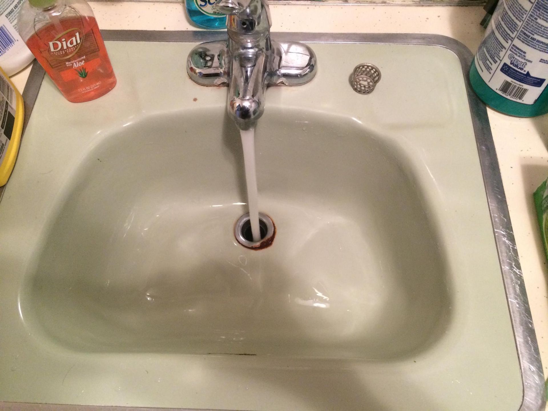 A sink with water running, with soap bottles visible on the side.