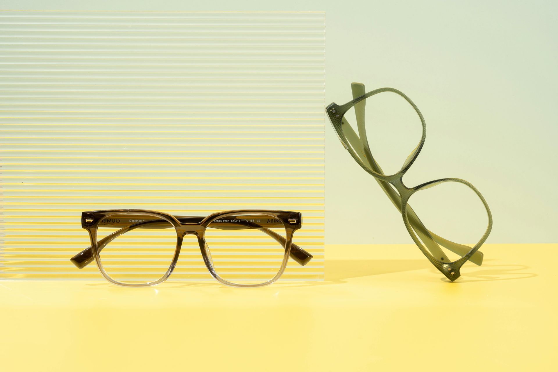 Two pairs of glasses are sitting on a yellow table.