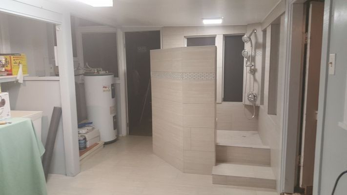 Small bathroom with a shower stall, steps, and water heater.