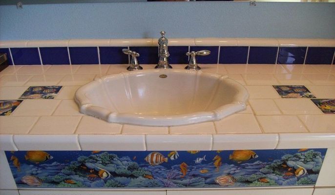 Bathroom vanity with a white sink, blue accents, and sea life tile details.