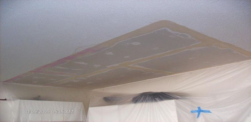 A room with the ceiling covered with plastic sheeting and tape. The walls are also covered.