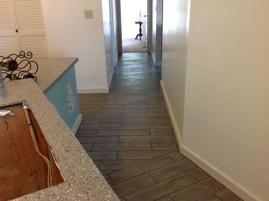 Hallway with light wood-look tile flooring and white walls. Countertop on the left.