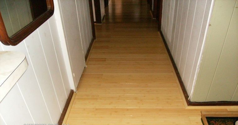 Wooden hallway with white paneled walls and a wooden floor.