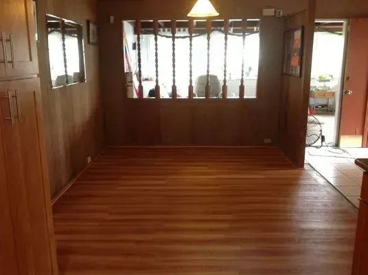 Empty dining room with wood paneling, wood floor, and a decorative window.