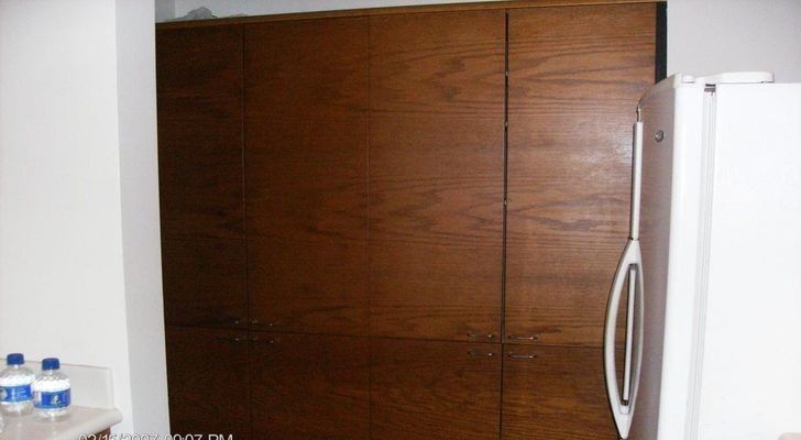 Dark wood cabinets next to a white refrigerator in a kitchen setting.