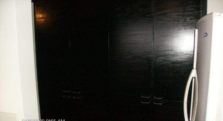 Black wooden pantry doors next to a white refrigerator.