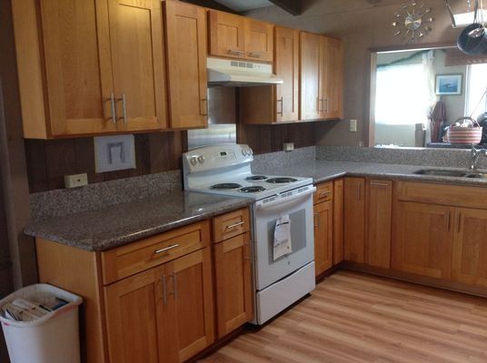 A kitchen with light brown cabinets, a white stove, and granite countertops.