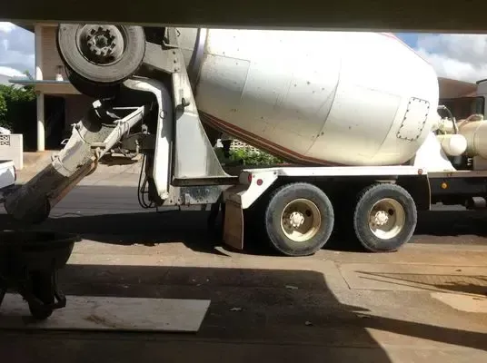 Cement truck parked, pouring concrete; gray, white, and tan colors.