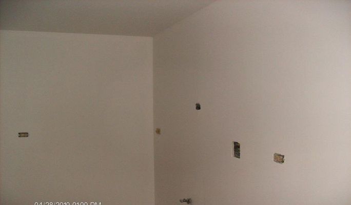Bare white walls of an interior corner with electrical outlet boxes.