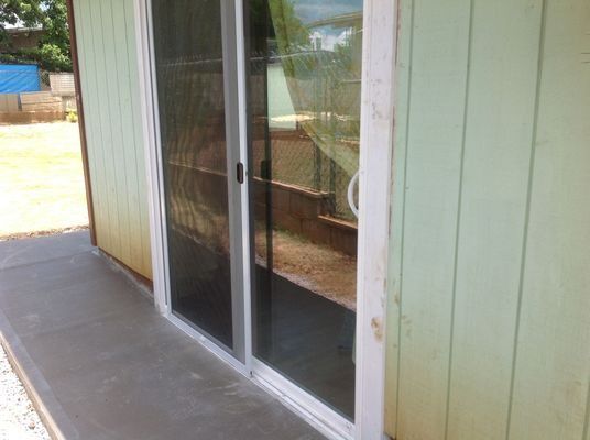 Sliding glass door, light green building exterior, concrete patio.
