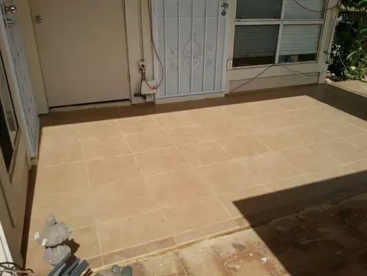 Beige tiled patio with a door, window, and shadows.