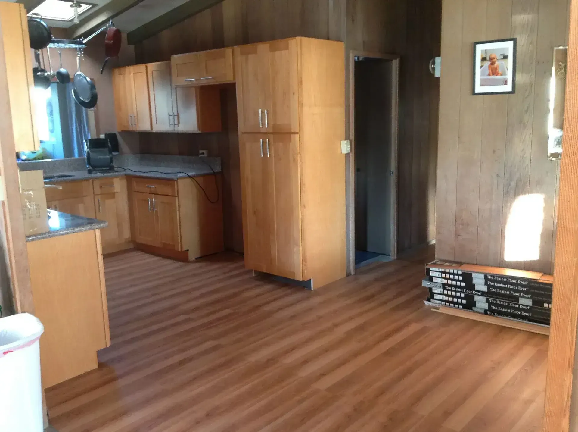Kitchen with wood cabinets, wood-look floor, and a tall, open pantry.