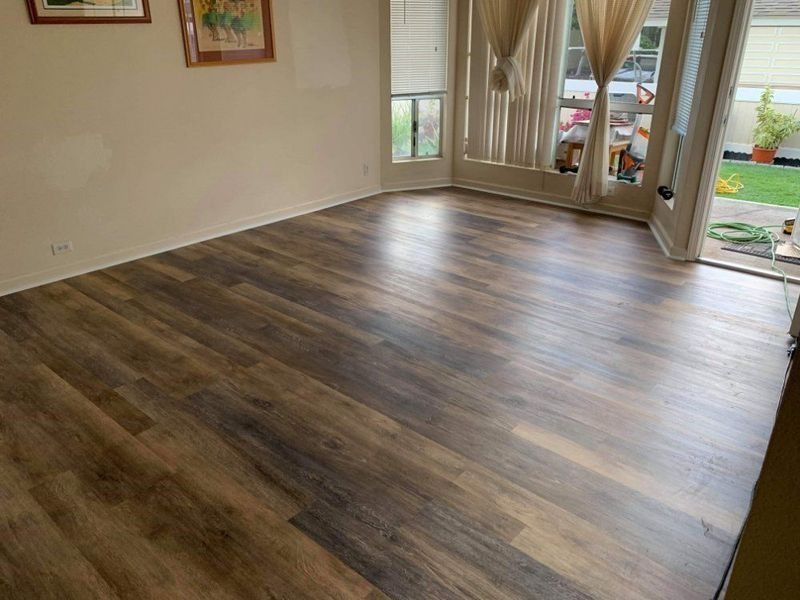 Hardwood-like flooring in a living space, with patio doors open to a backyard.