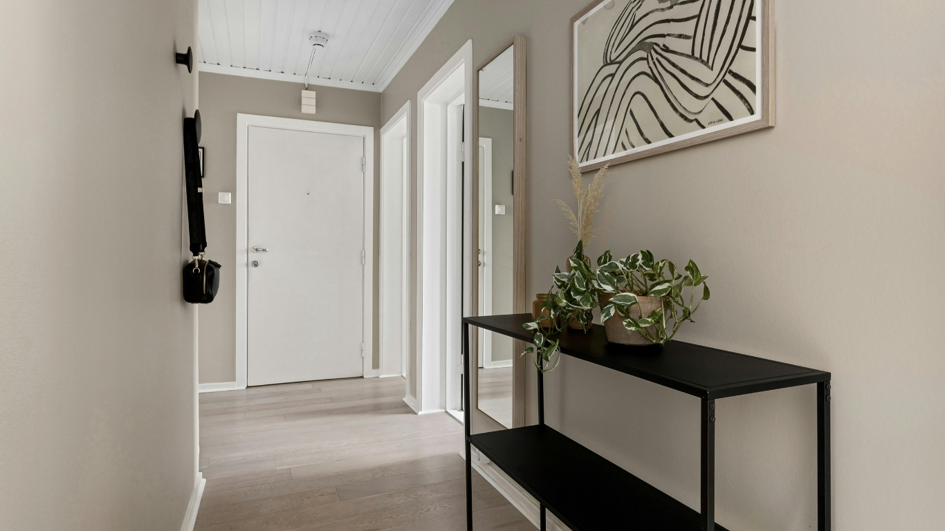 Hallway with a black console table, mirror, and artwork on a light gray wall.
