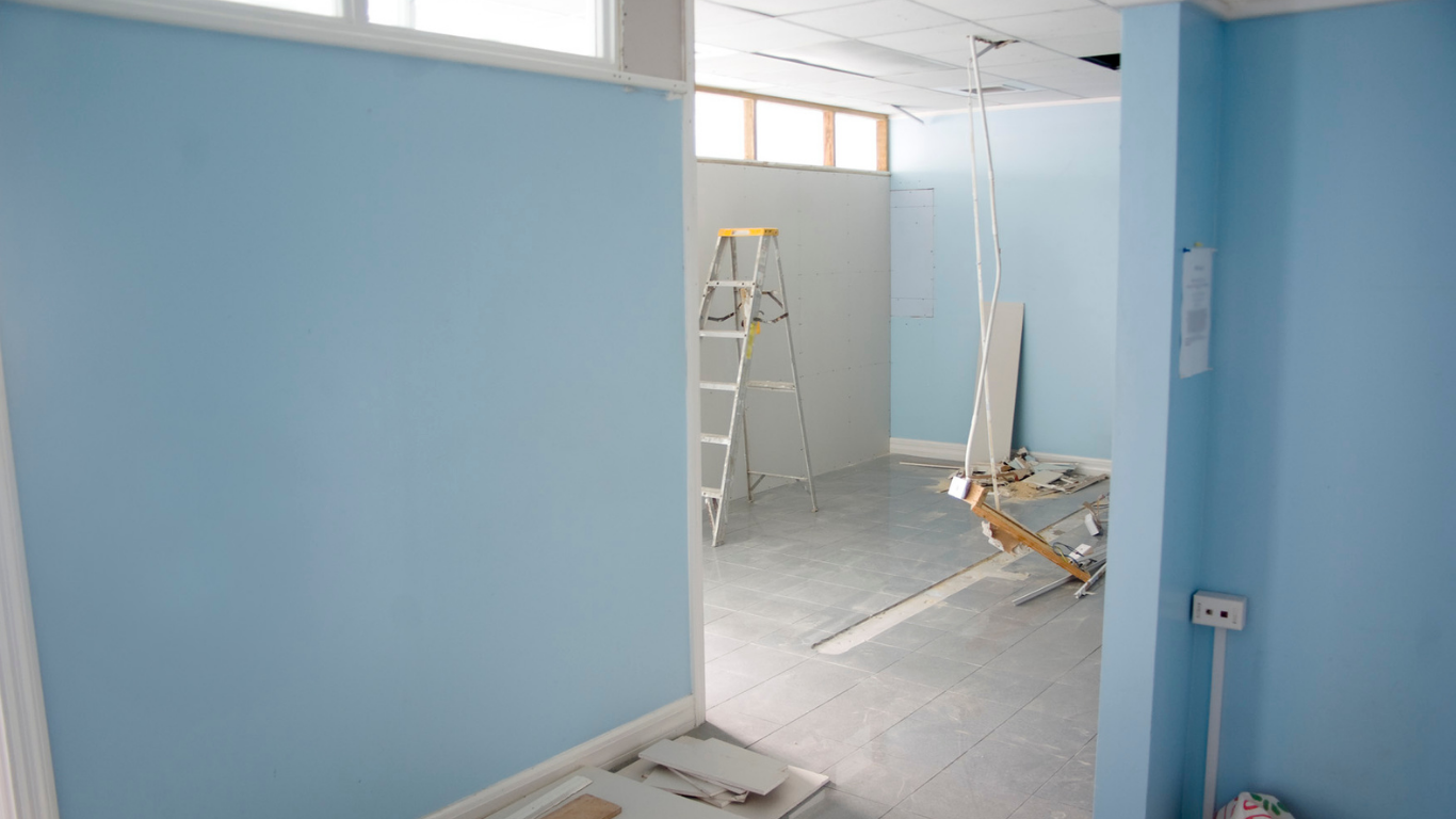 Room interior with light blue walls, construction materials, and a ladder.