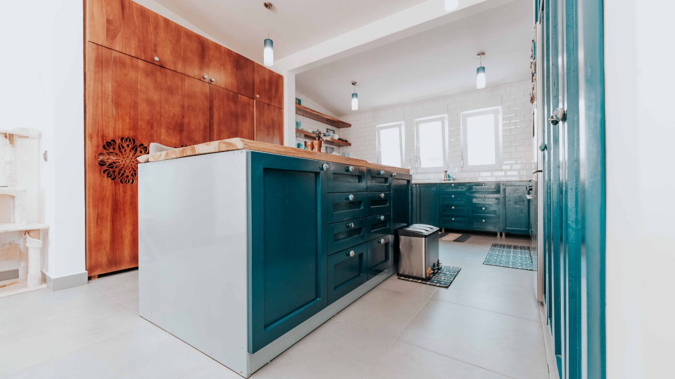 Kitchen with teal cabinets, wood island, and large wooden wall cabinet.