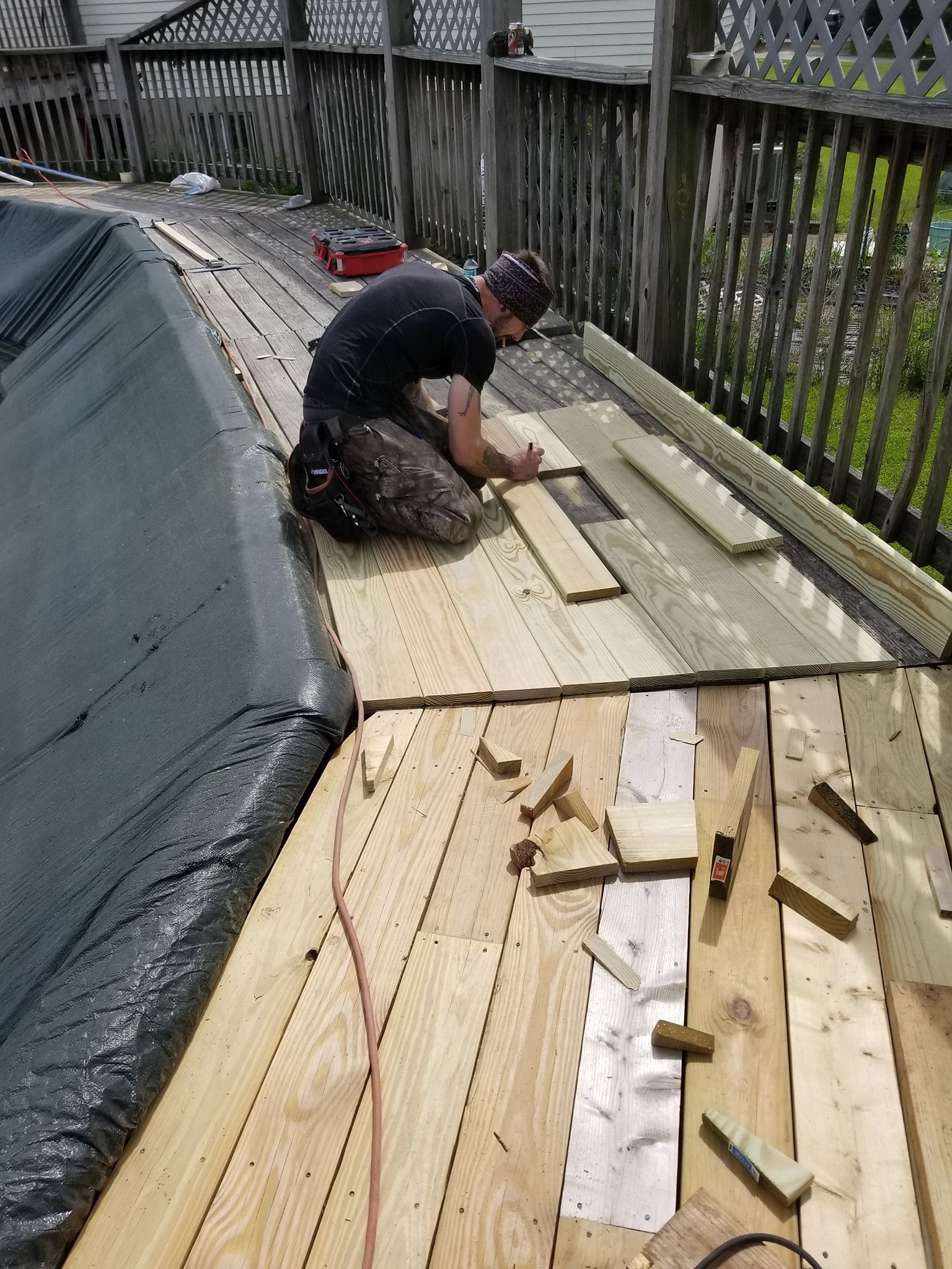 A man is kneeling down on a wooden deck.