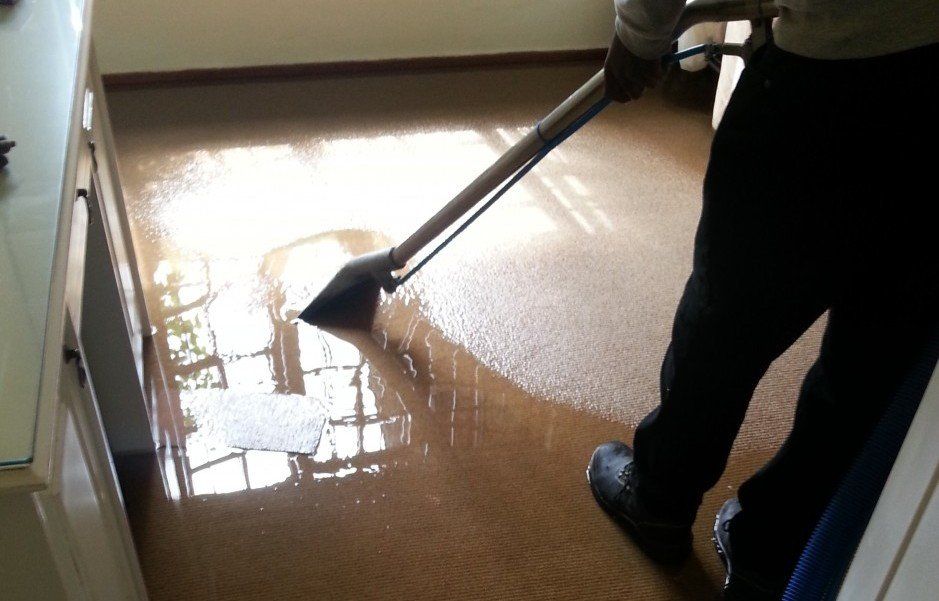 A person is using a vacuum cleaner to clean a flooded floor