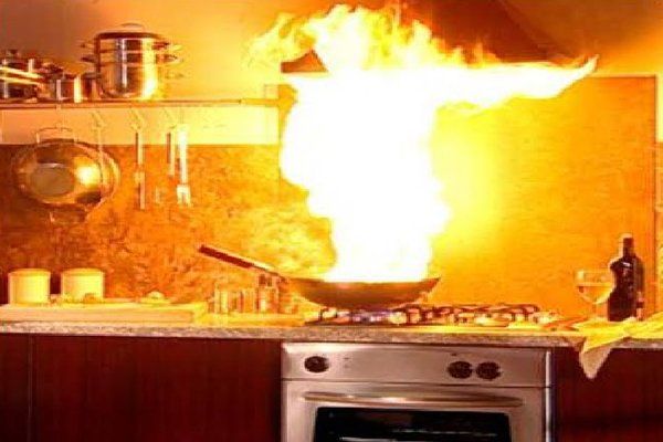 A frying pan on a stove with flames coming out of it