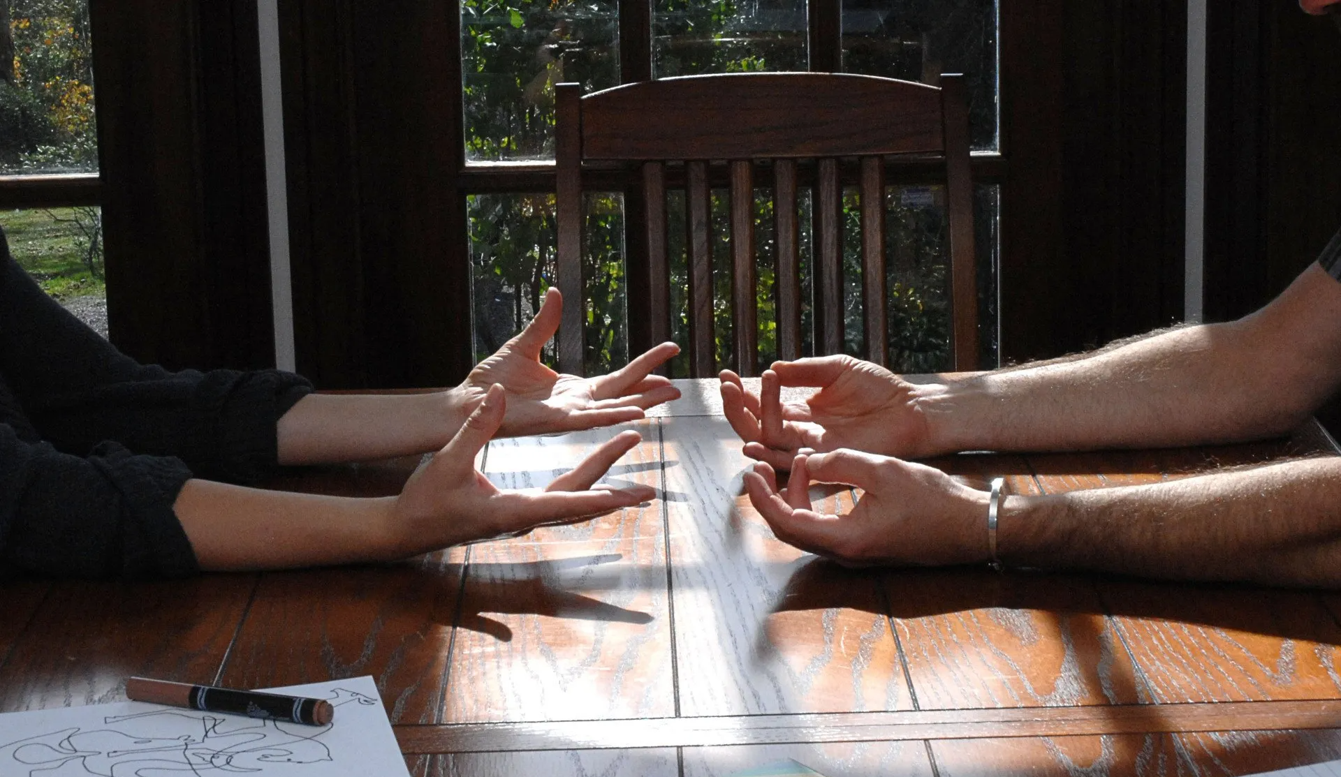 Two people are sitting at a table with their hands outstretched