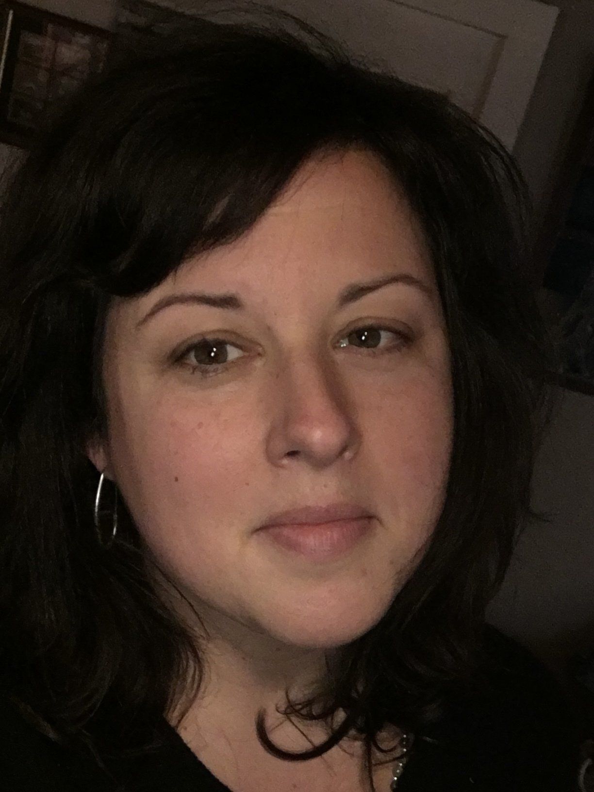 A close up of a woman 's face wearing a black shirt and earrings.