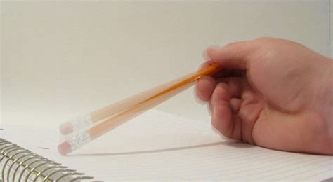 A person is holding a pencil over a notebook.