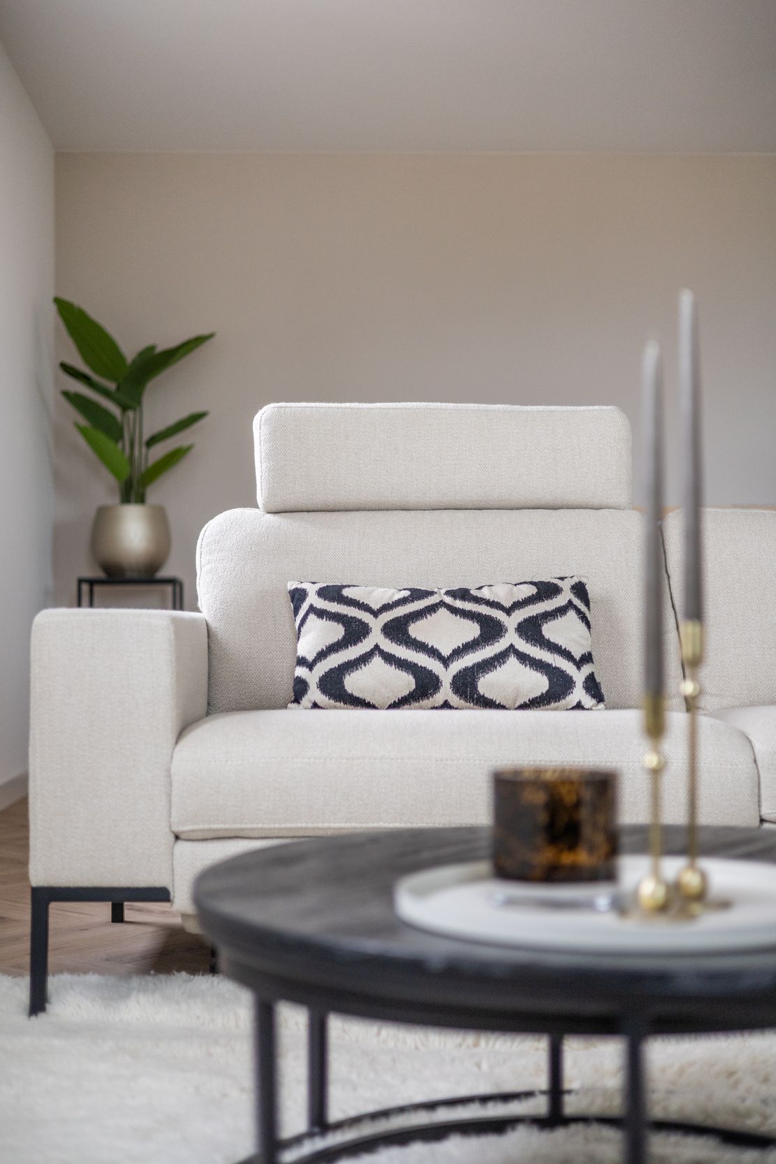 Eethoek: ronde tafel met vier lichte stoelen, houten lamellenwand, glazen hanglampen, planten.