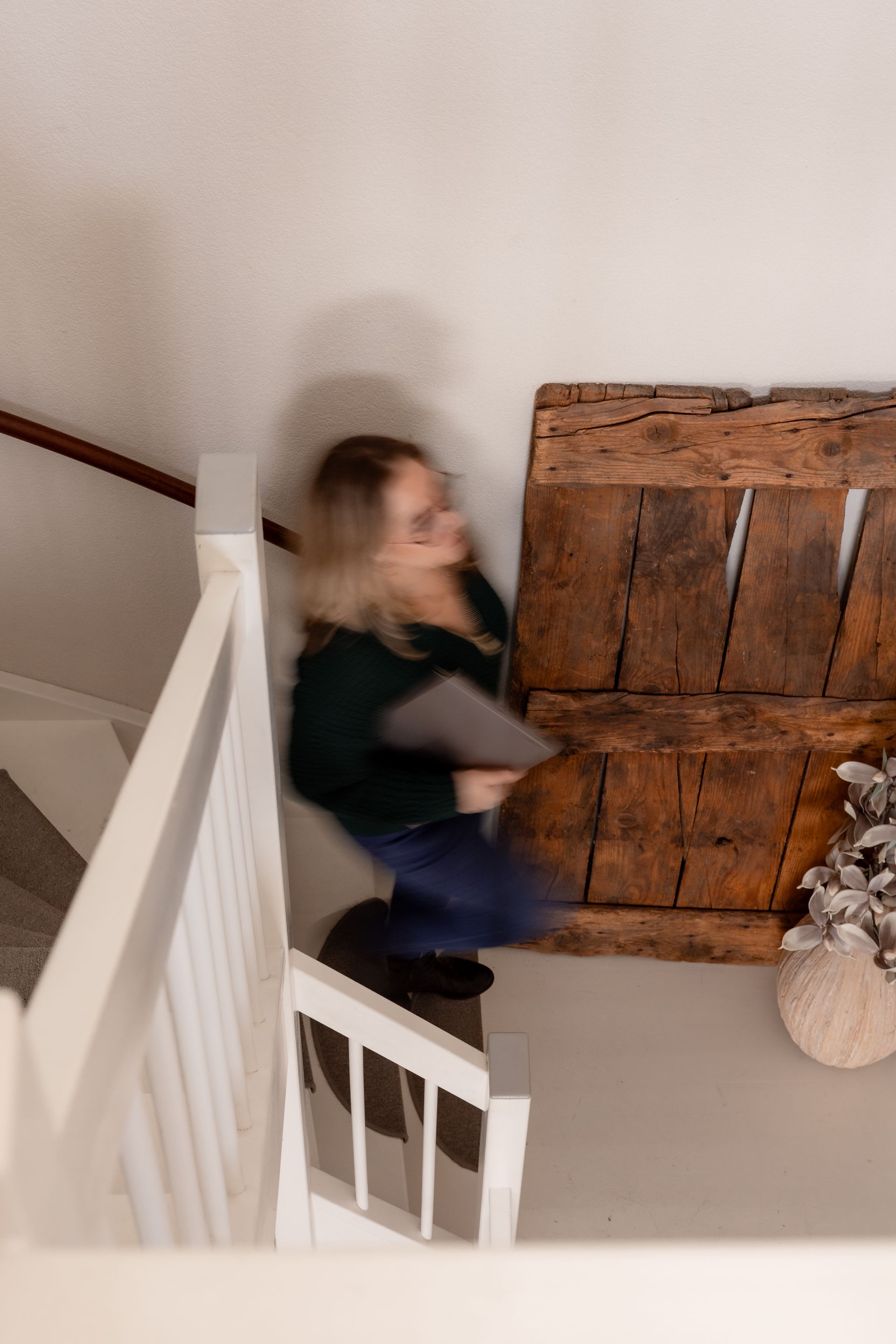 Eethoek: ronde tafel met vier lichte stoelen, houten lamellenwand, glazen hanglampen, planten.