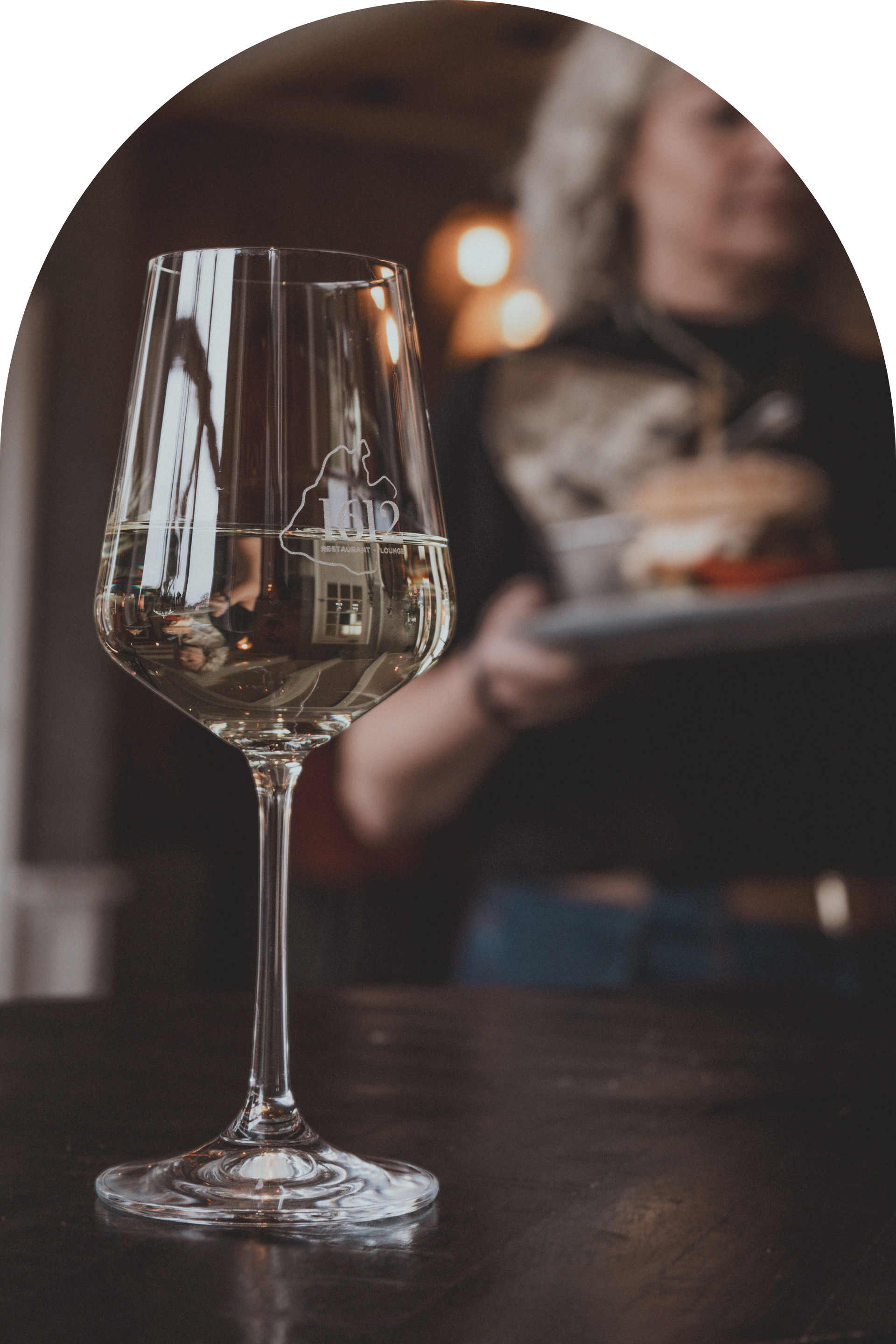 Eethoek: ronde tafel met vier lichte stoelen, houten lamellenwand, glazen hanglampen, planten.