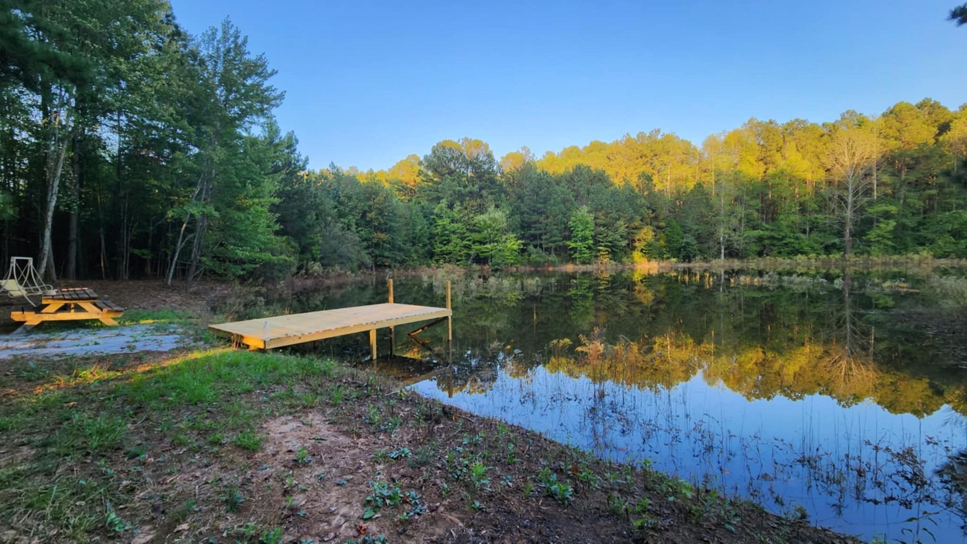 There is a dock in the middle of a lake surrounded by trees.