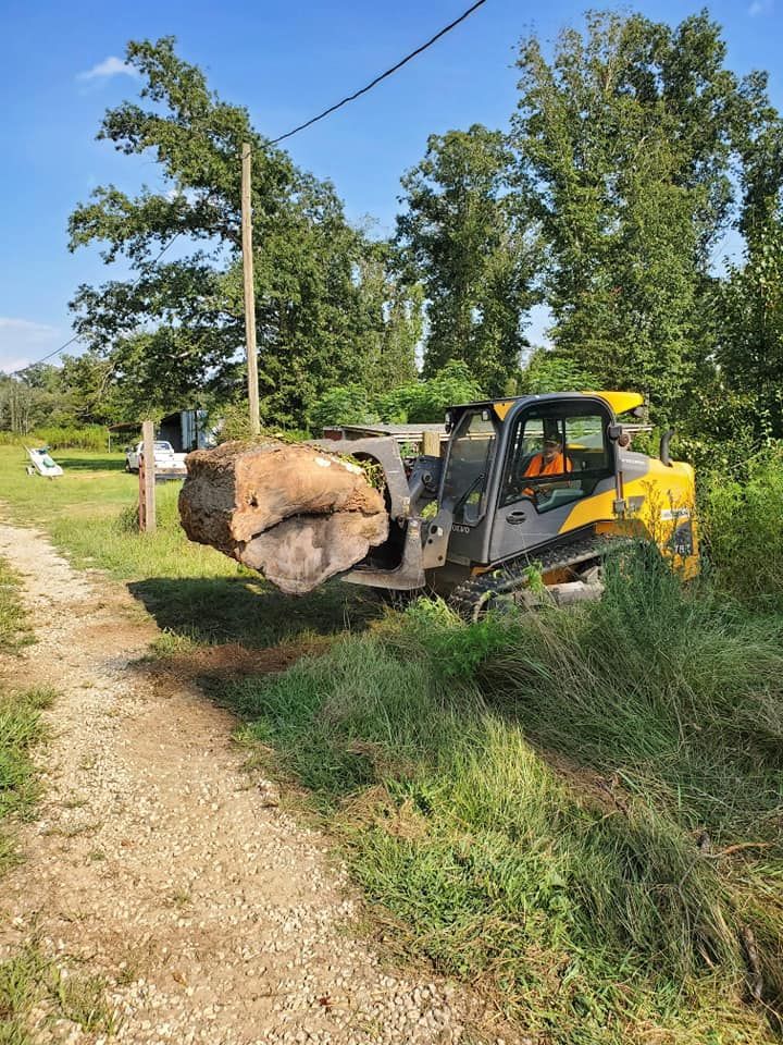A bulldozer is carrying a large rock down a dirt road.