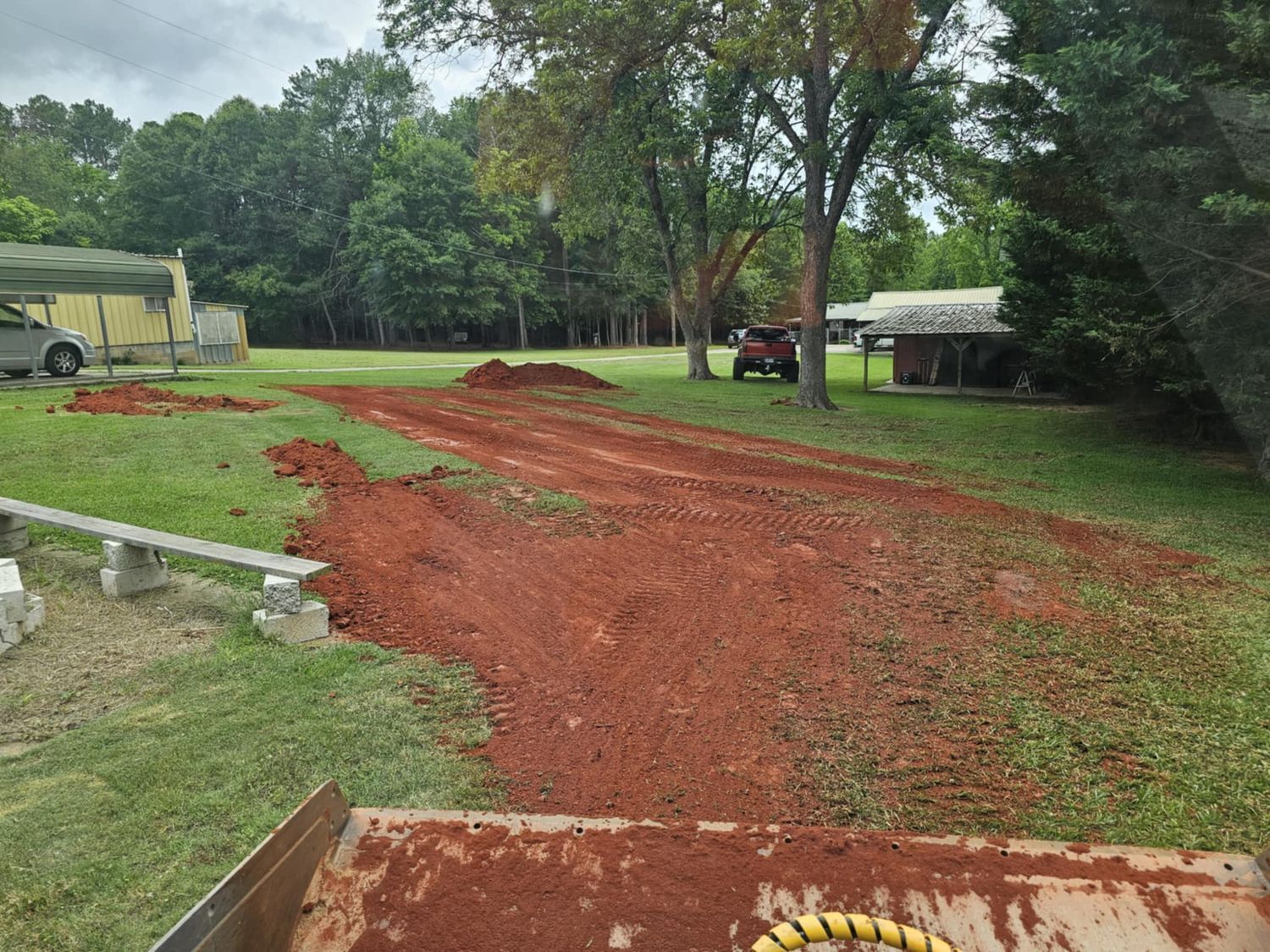 A dirt road leading to a house with trees in the background.