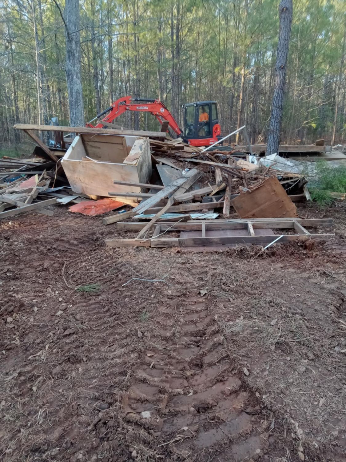 A large pile of wood is sitting in the middle of a dirt field.