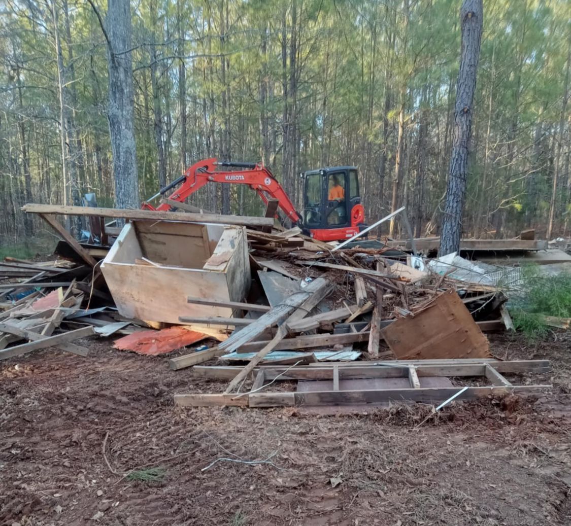 A red excavator is sitting on top of a pile of wood.